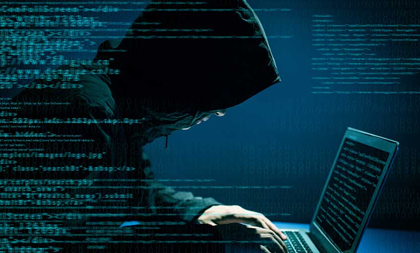 Person in a hoodie working on a computer, engaged in hacking