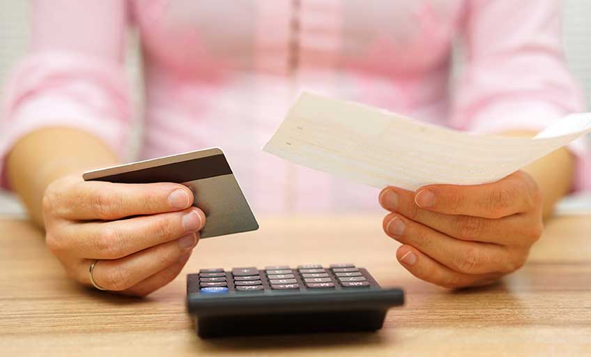 Person using a calculator while holding a check