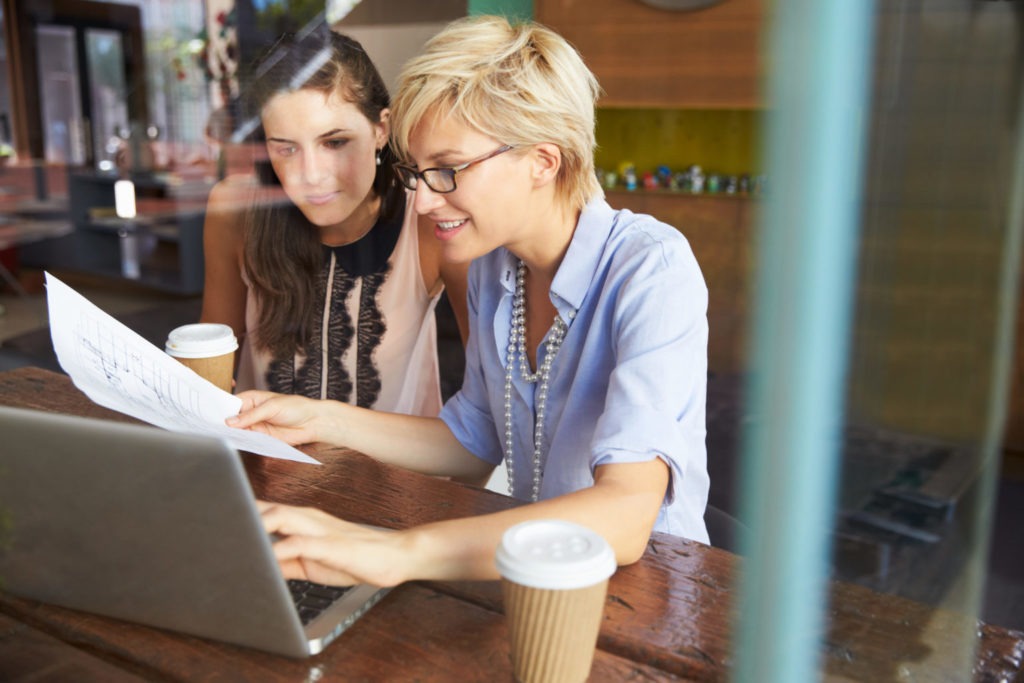 Two women looking at a laptop and discussing.