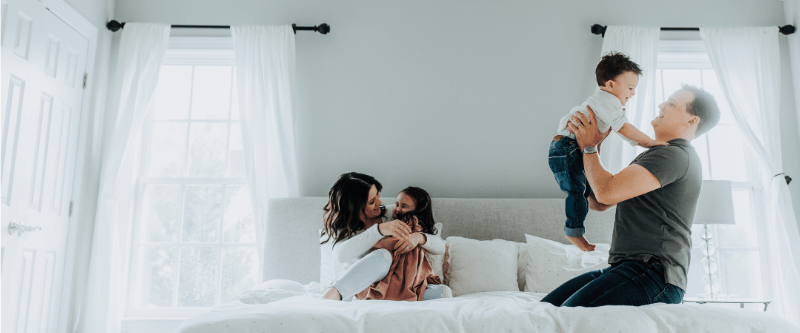 Family at home together with a mom, dad and two kids candidly having fun. 